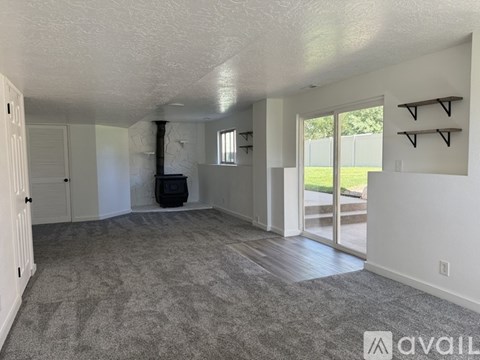 A spacious room with a grey carpet and white walls.