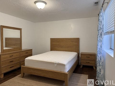 A bedroom with a bed, dresser, and mirror.