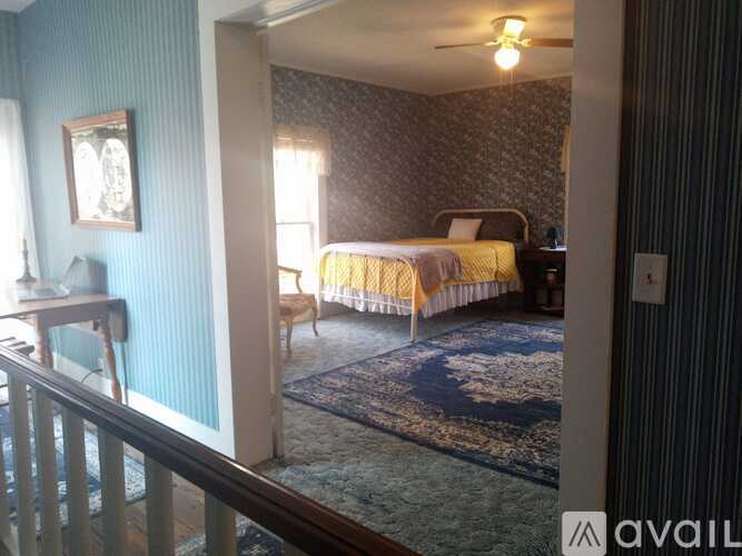 A bedroom with a bed, a chair, and a rug.