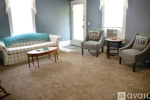 A living room with a sofa, two chairs, and a table.