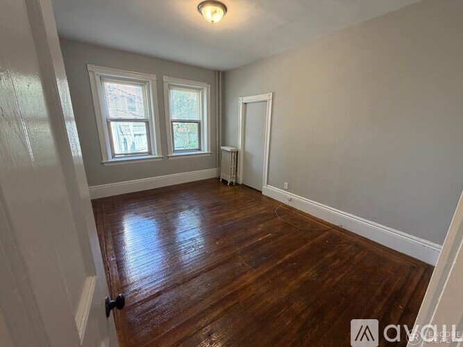 A room with wooden floors and two windows.