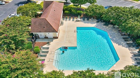 An aerial view of a swimming pool surrounded by trees and a building.