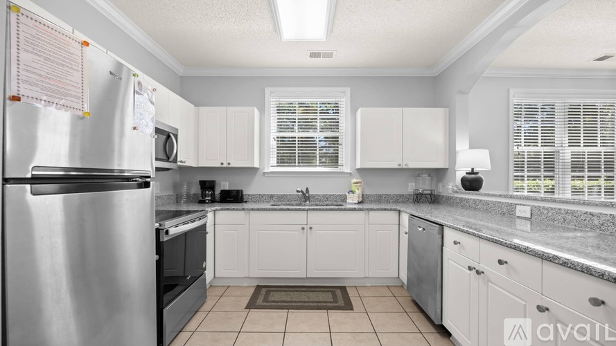 A kitchen with white cabinets and a stainless steel refrigerator.