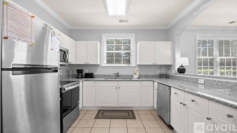 A kitchen with white cabinets and a stainless steel refrigerator.