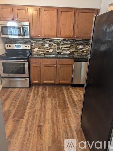A kitchen with wooden cabinets and a black fridge.
