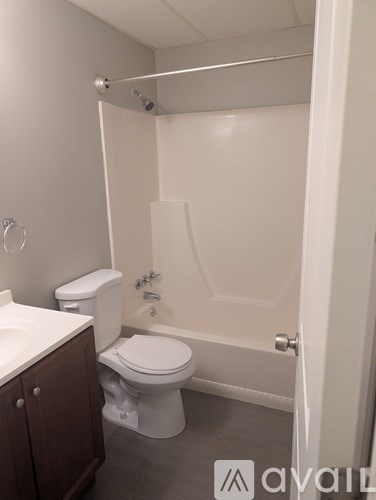A white toilet is in a bathroom with a white tub.