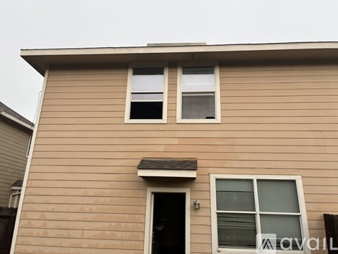 A house with a brown facade and two windows, one of which is open.