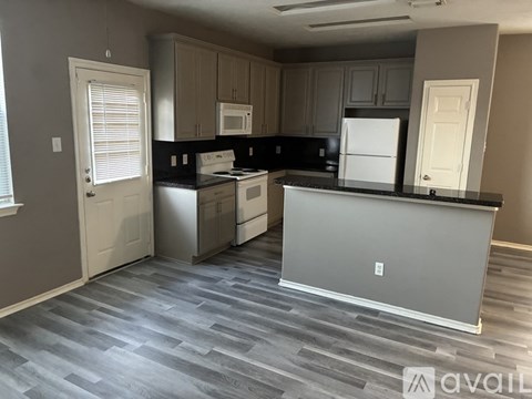 A kitchen with a white refrigerator and black countertops.