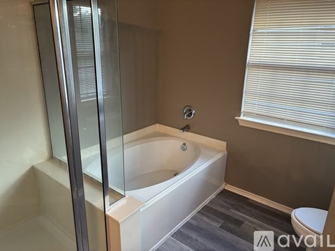 A modern bathroom with a glass shower door and a white bathtub.