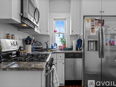 A kitchen with a stove, refrigerator, and various items on the counter.