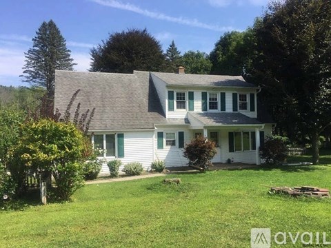 A house with a green lawn and trees in the background.