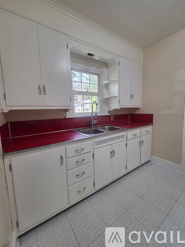 A kitchen with white cabinets and a red backsplash.