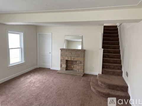 A living room with a fireplace and stairs leading to the upper floor.