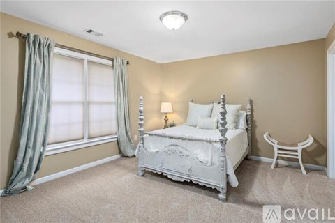 A bedroom with a large bed and a chair.