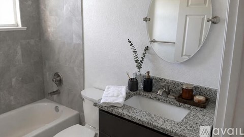A bathroom with a white toilet, a bathtub, and a granite countertop.