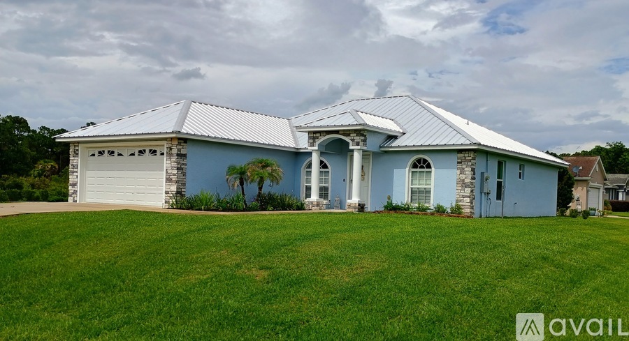 A house with a blue exterior and a white roof is available for sale.
