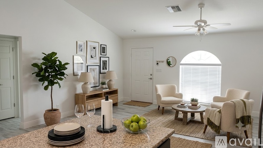 A living room with a couch, chair, and a table with a bowl of fruit on it.