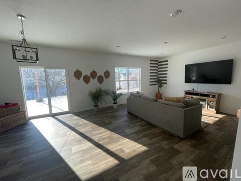 A living room with a grey couch and a television on the wall.