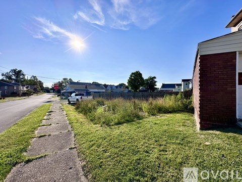A sunny day on a residential street with a white car parked on the side.