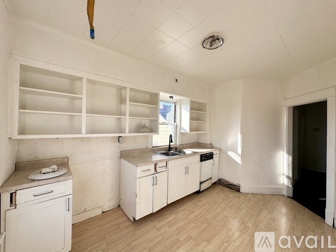 A kitchen with white appliances and wooden floors.