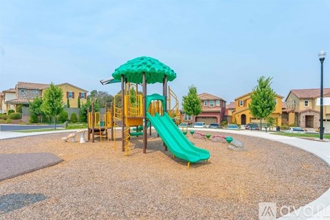 A playground with a green slide and a yellow structure.