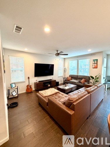 A living room with a brown couch and a television on the wall.