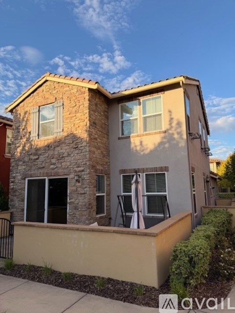 A two-story house with a stone facade and a beige exterior.