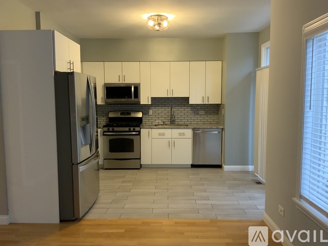 A kitchen with white cabinets and a wooden floor.