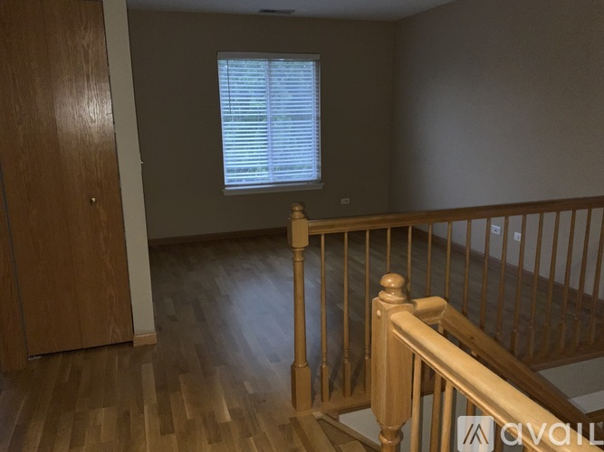 A room with wooden floors and a window with blinds.