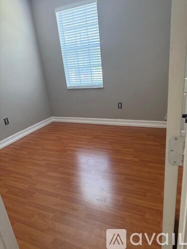 A room with wooden flooring and a window with blinds.