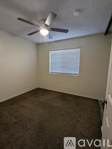 A room with a ceiling fan and carpeted floor.