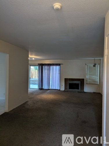 A living room with a fireplace and a window with curtains.