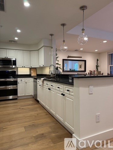 A kitchen with white cabinets and wooden floors.
