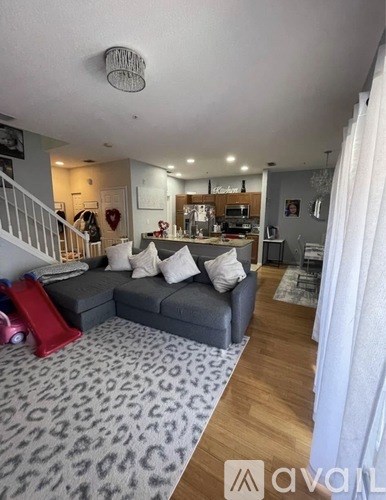 A living room with a grey couch and a leopard print rug.