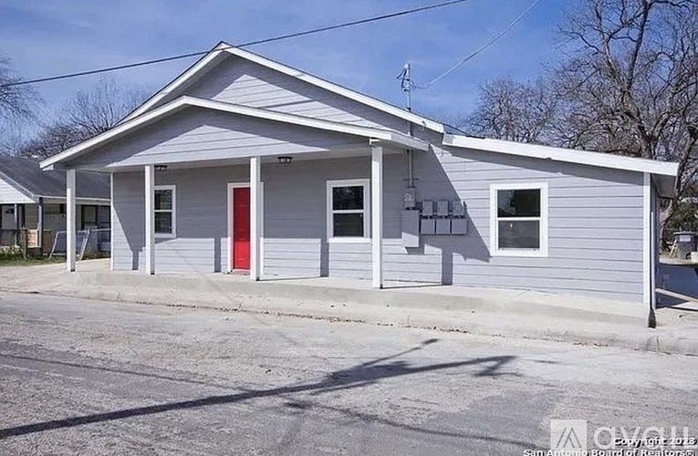 A small building with a red door and a grey roof.