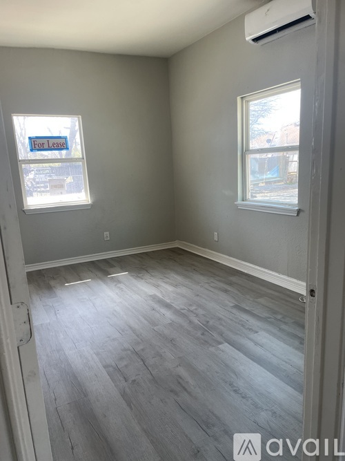 A room with a grey floor and two windows.