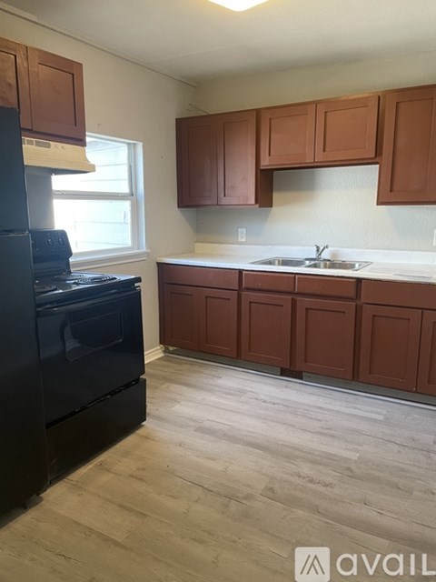 A kitchen with brown cabinets and a black stove top oven.