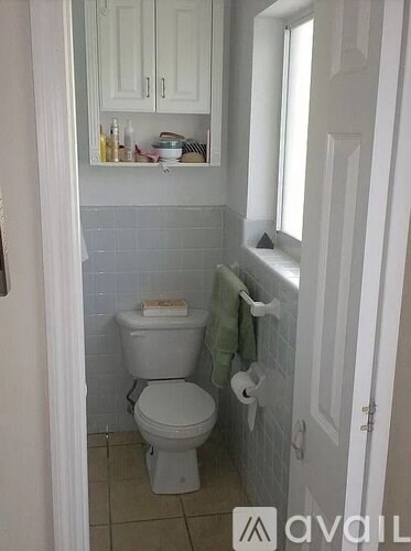 A white toilet with a towel hanging on the towel rack.
