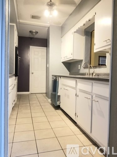 A kitchen with white cabinets and a grey floor.