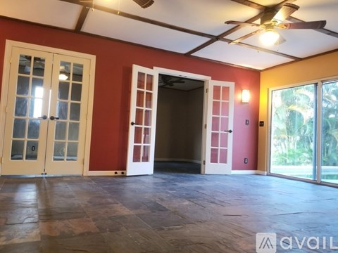 A room with a ceiling fan and sliding glass doors.