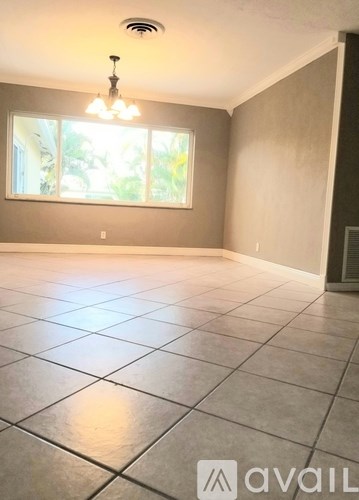 A spacious room with tiled flooring and a chandelier.