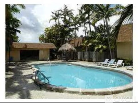 A small pool surrounded by trees and chairs.