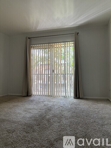 A room with a carpeted floor and a sliding door leading outside.
