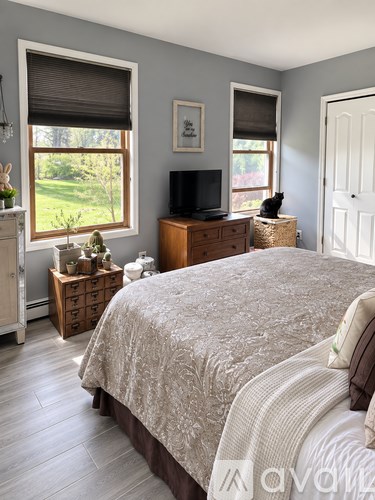 A bedroom with a large bed and a window with blinds.