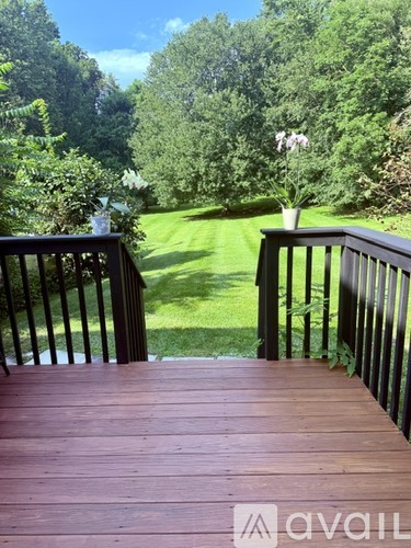 A wooden deck with a view of a green lawn and trees.