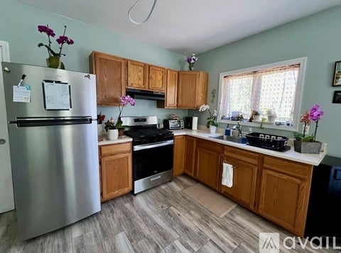 A kitchen with wooden cabinets and a stainless steel refrigerator.