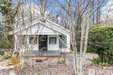 A white house with a porch and a tree in front.