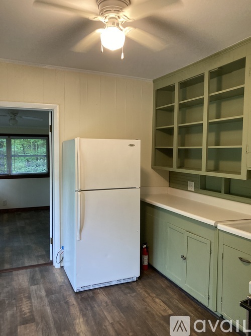 A white refrigerator in a kitchen with green cabinets.