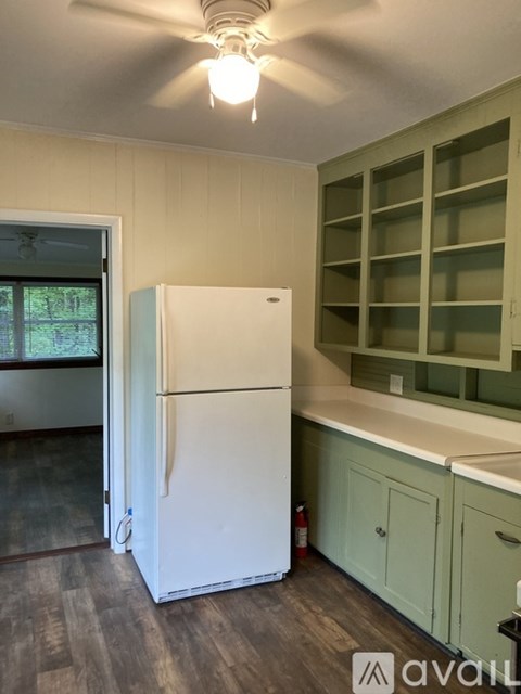 A white refrigerator in a kitchen with green cabinets.