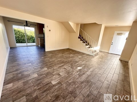 A spacious room with wooden flooring and a staircase leading to another level.